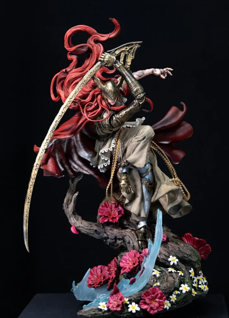 Estátua de Malenia de corpo inteiro, lâmina curva erguida, cabelo vermelho ao vento e capa aberta sobre base de raiz com flores